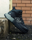 New balance athletic safety shoe with brand logo on a concrete step and brick wall background
